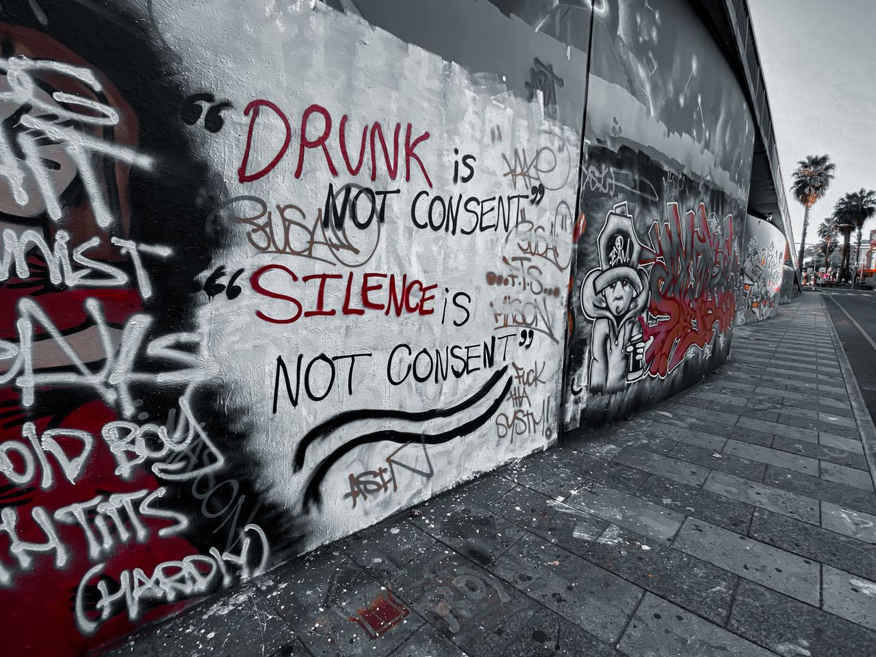 Graffiti art emphasizing consent with bold text on urban street wall.