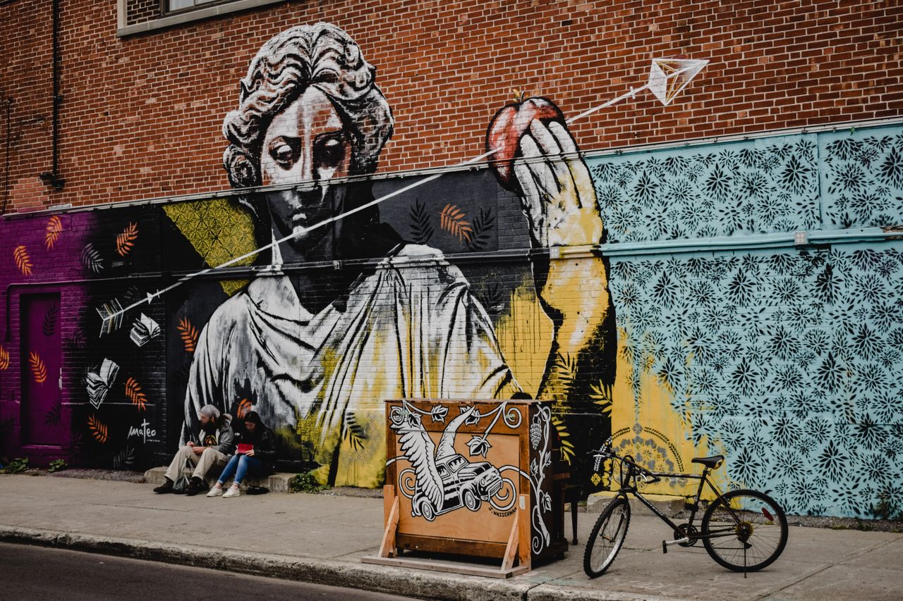 A vibrant mural depicting classical art on a brick wall in Montreal, Canada.